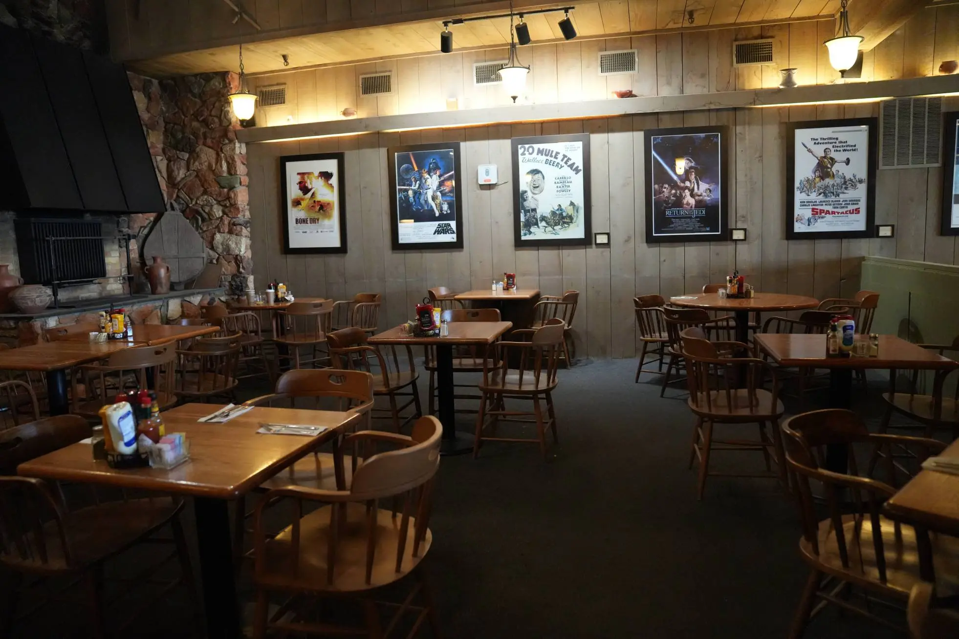 restaurant tables with lighting above a set of poster on the back wall